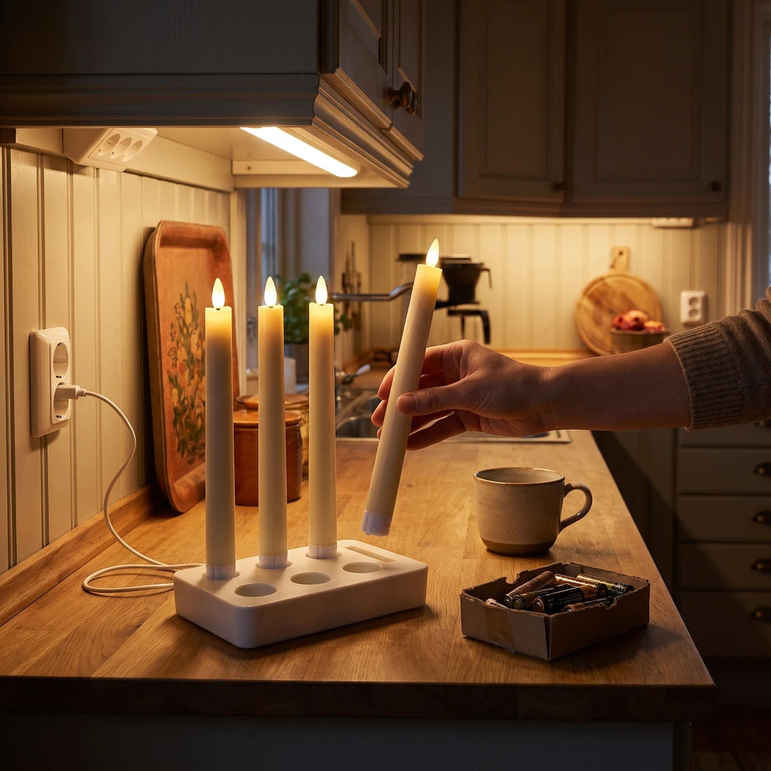 Una mano rimette una candela Ceriva™ nella base di ricarica sul piano della cucina, accanto a una scatola di vecchie pile